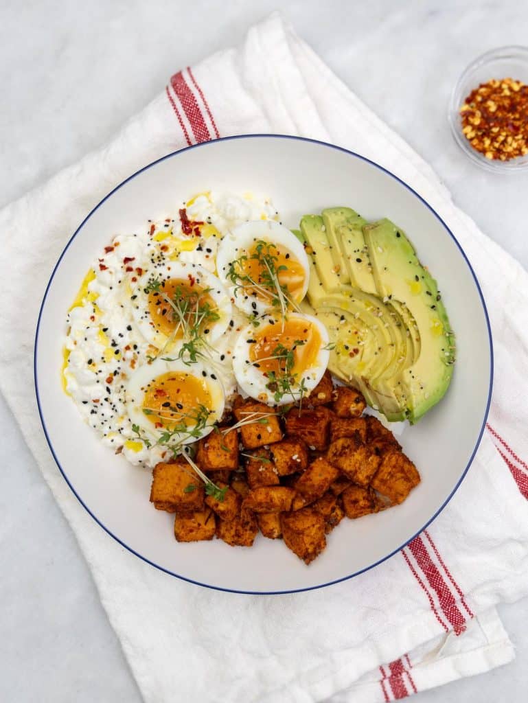 Savory cottage cheese breakfast bowl with soft-boiled eggs, avocado, sweet potato, and everything bagel seasoning