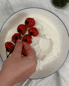 Adding diced cucumber to a greek yogurt base with blistered cherry tomatoes