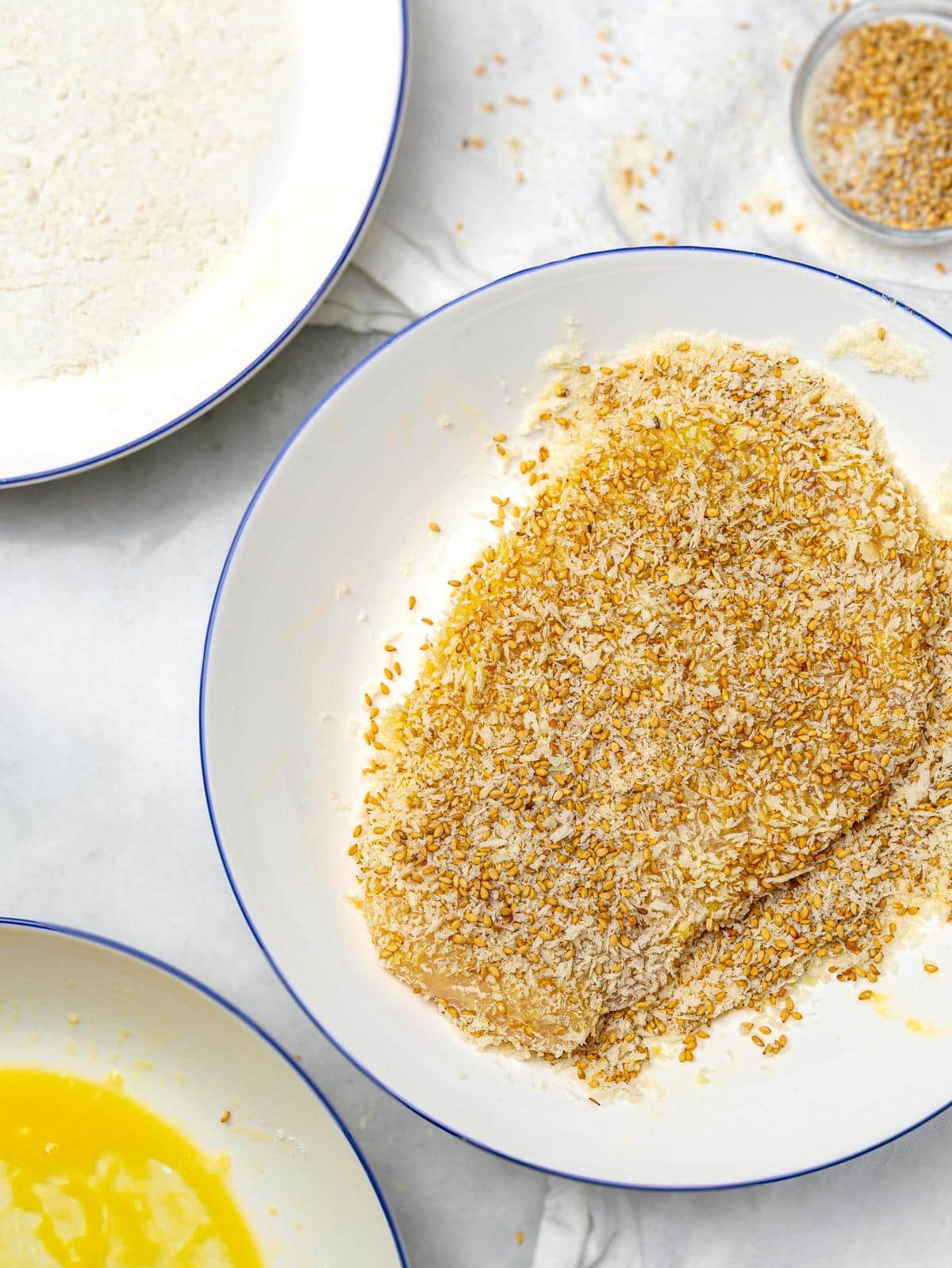 Chicken cutlet dredged in panko and sesame seed coating with flour and egg