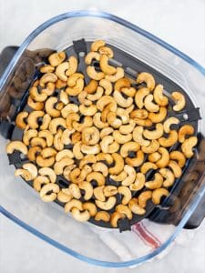 Toasted cashews in a single layer in an air fryer basket