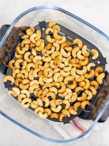 Toasted cashews in an air fryer basket for cashew chicken salad