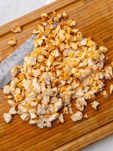 Finely chopped seasoned chicken breast on a wooden cutting board