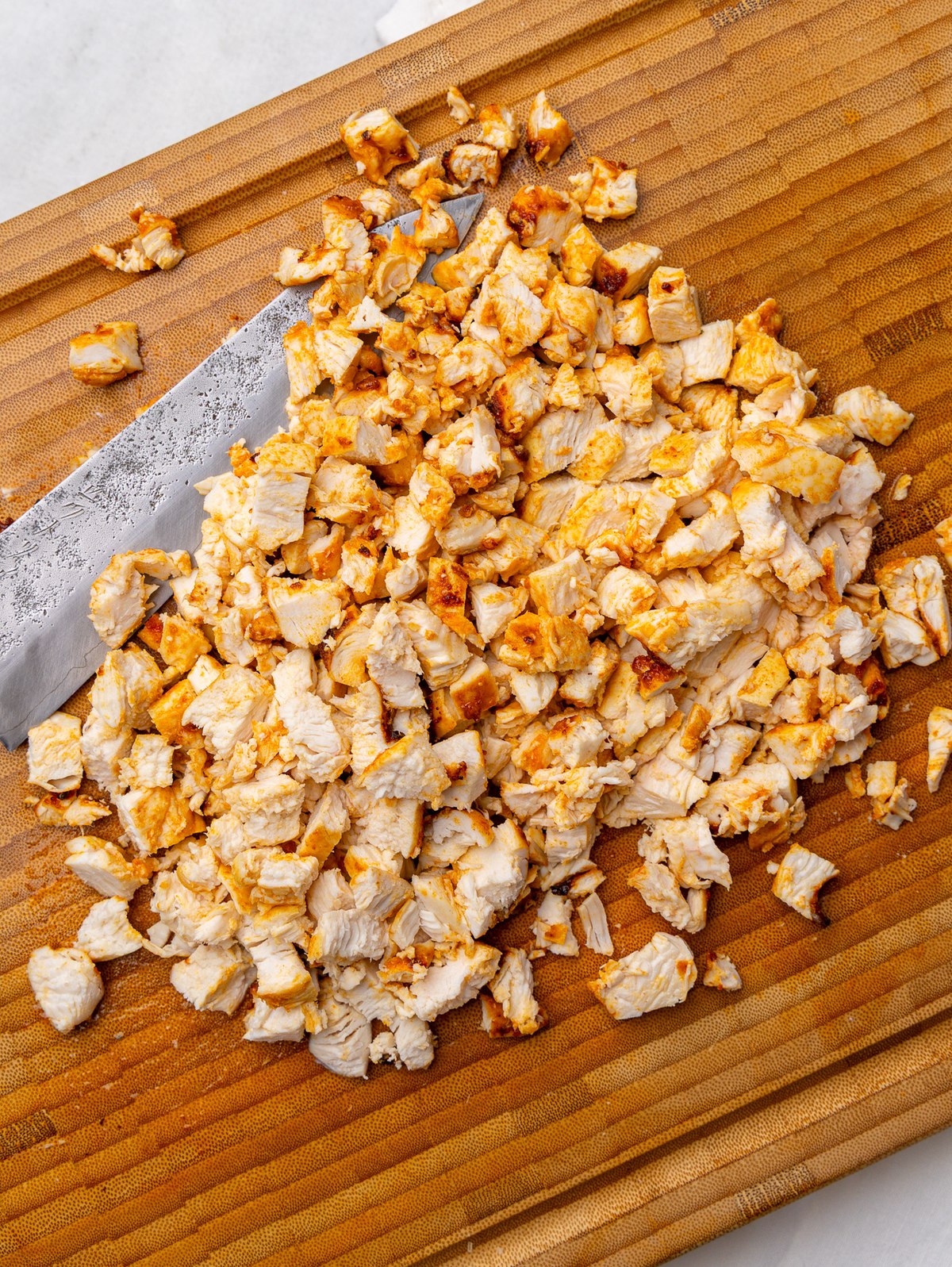 Finely chopped seasoned chicken breast on a wooden cutting board