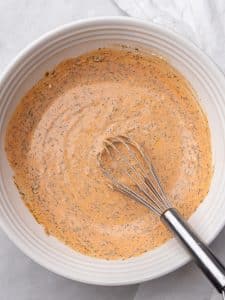 Creamy buffalo chicken pasta salad dressing whisked smooth in a white bowl