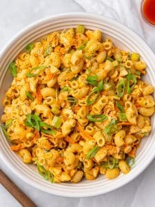Healthy buffalo chicken pasta salad topped with green onions in a large white bowl