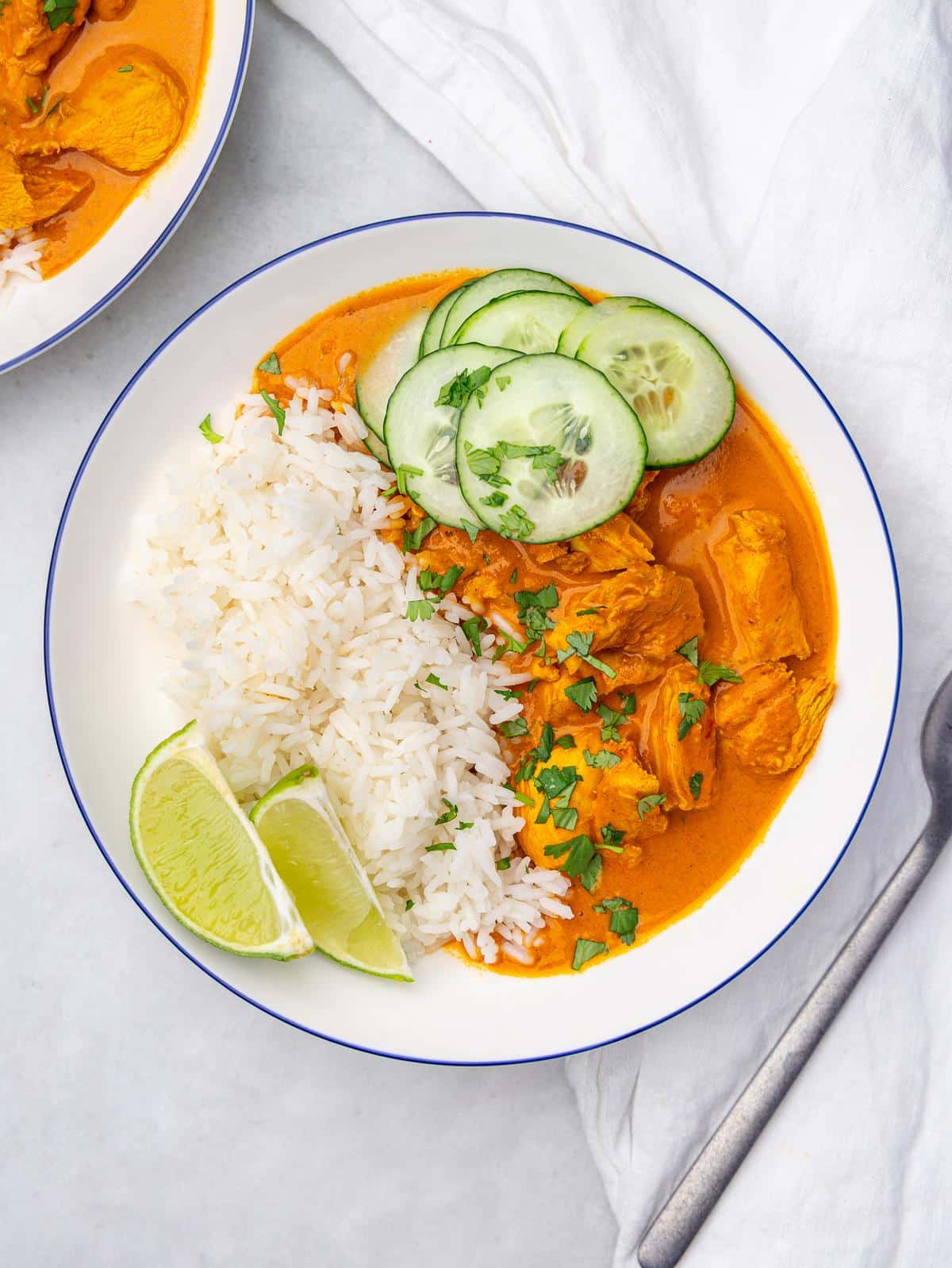 Coconut chicken rice bowl with jasmine rice, cucumber slices, lime wedges, and fresh cilantro