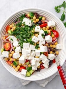 Greek chickpea salad topped with cubed feta and chopped fresh parsley before mixing