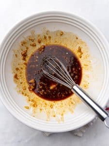 Hawaiian chicken marinade with soy sauce, ketchup, brown sugar, and garlic whisked together in a white bowl