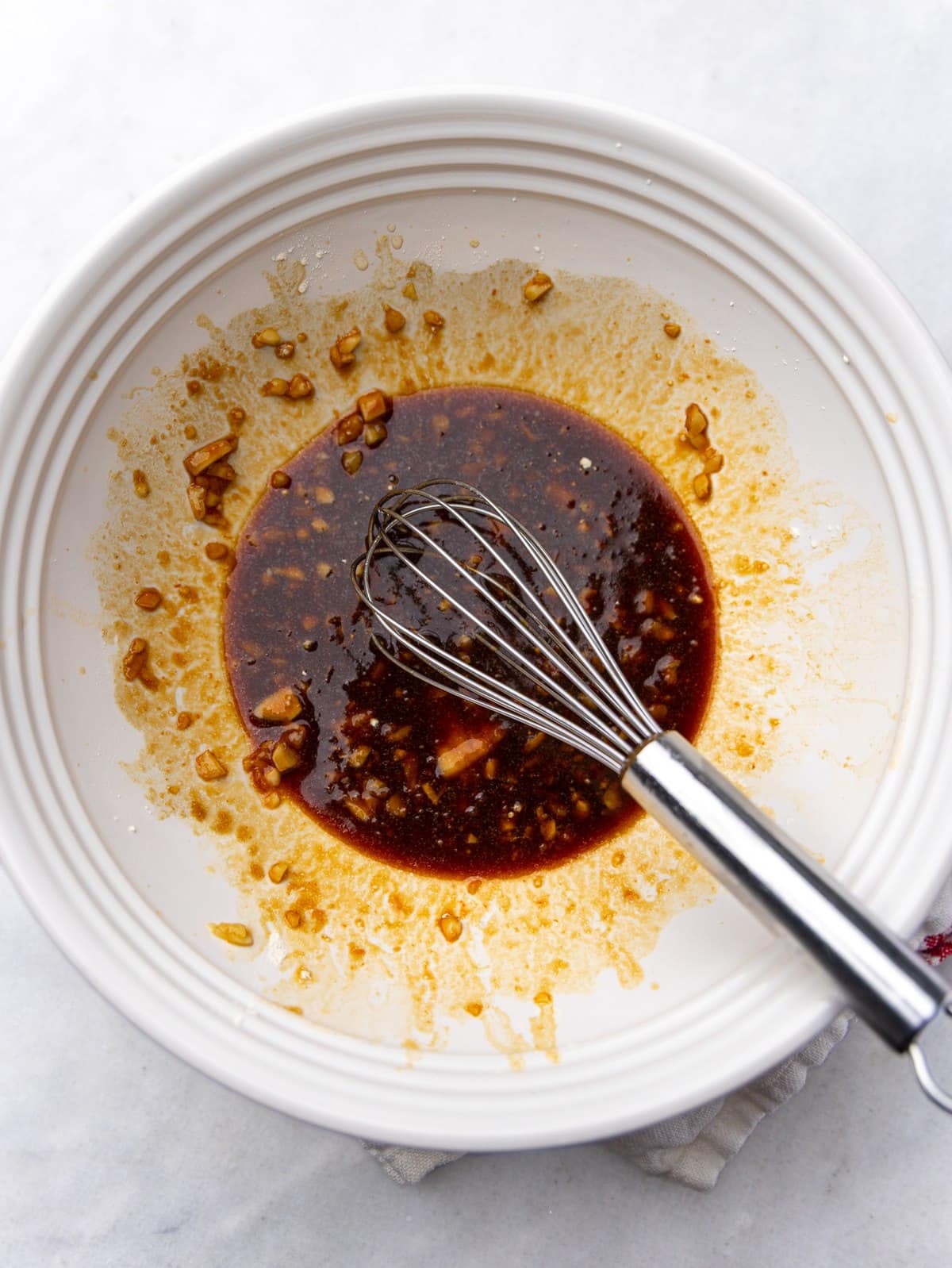Hawaiian chicken marinade with soy sauce, ketchup, brown sugar, and garlic whisked together in a white bowl