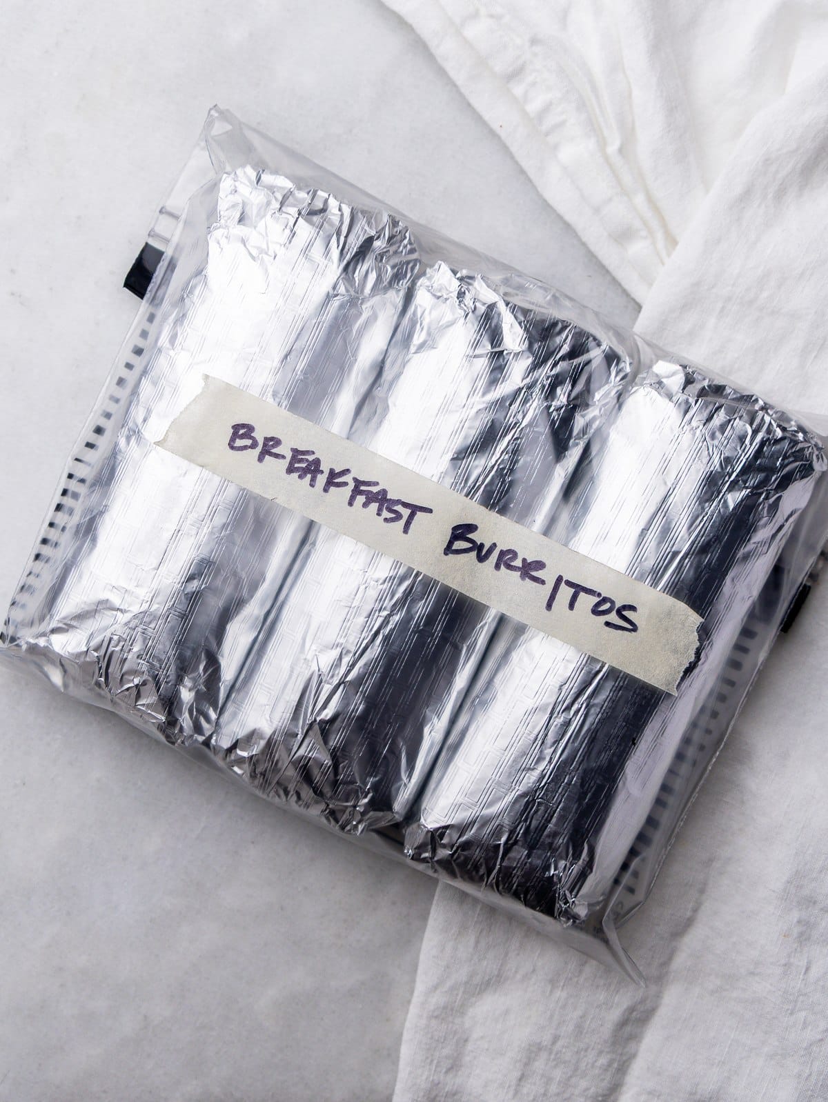 Foil wrapped high protein breakfast burritos in a labeled freezer bag