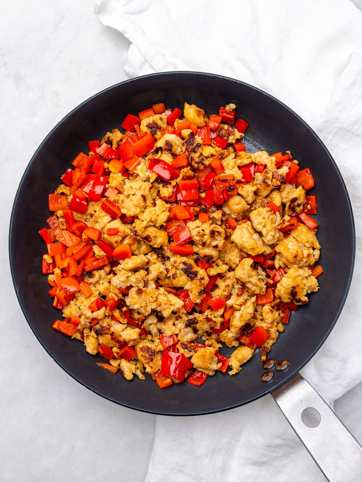 Crumbled turkey breakfast sausage and diced red bell pepper browning in a skillet