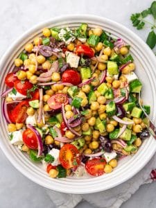 High-protein chickpea salad with cherry tomatoes, cucumber, feta, and kalamata olives in a white bowl