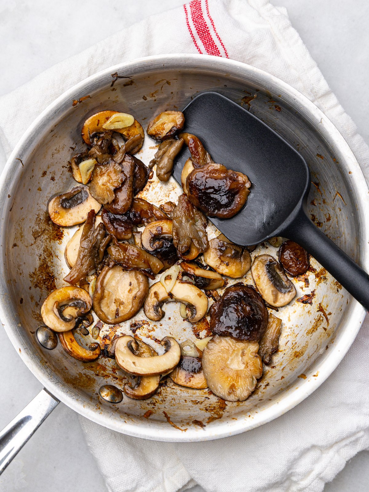 Dry-seared mixed mushrooms with sliced garlic in a stainless steel skillet