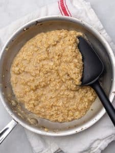Creamy savory oatmeal cooked in bone broth in a skillet with a spatula