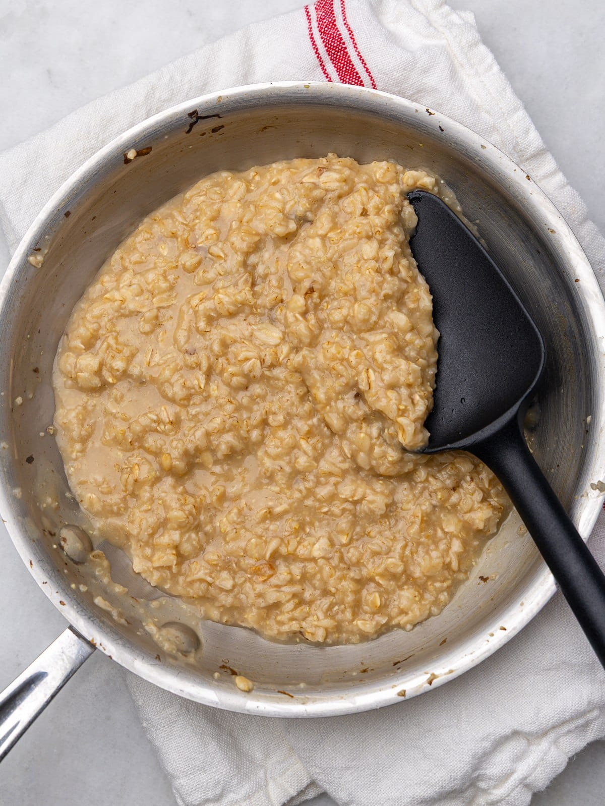 Creamy savory oatmeal cooked in bone broth in a skillet with a spatula