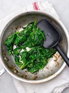 Wilted spinach with chili flakes in a skillet for savory oatmeal