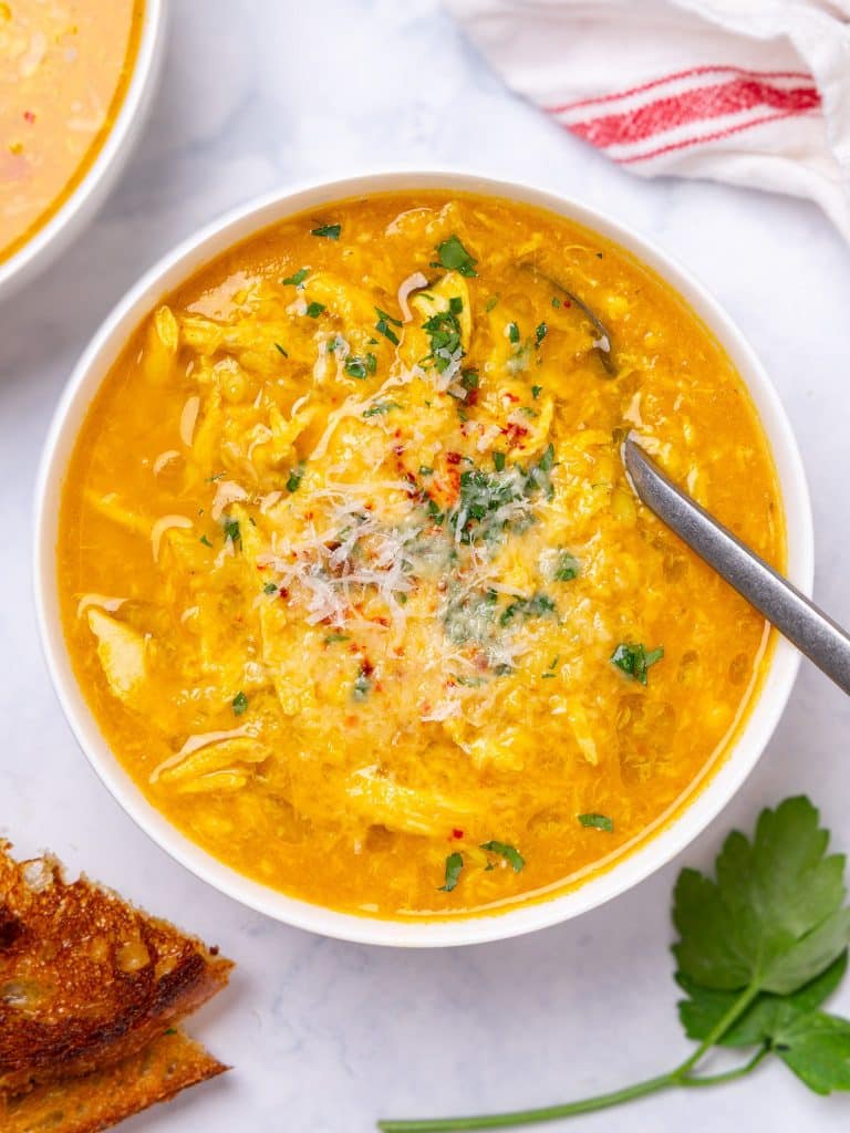Easy italian penicillin soup with shredded chicken, pastina, parmesan and fresh parsley in a white bowl
