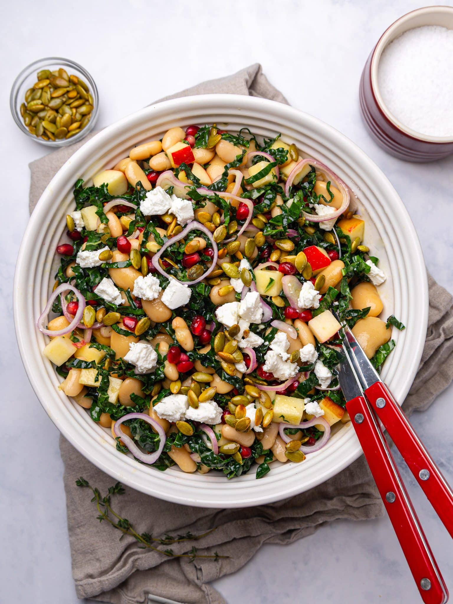 Fall harvest dense bean salad tossed in a large white bowl with serving tongs