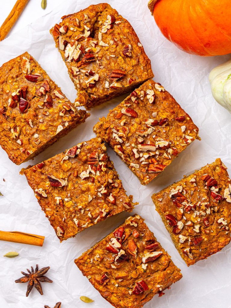 High-protein pumpkin baked oatmeal cut into squares and topped with chopped pecans