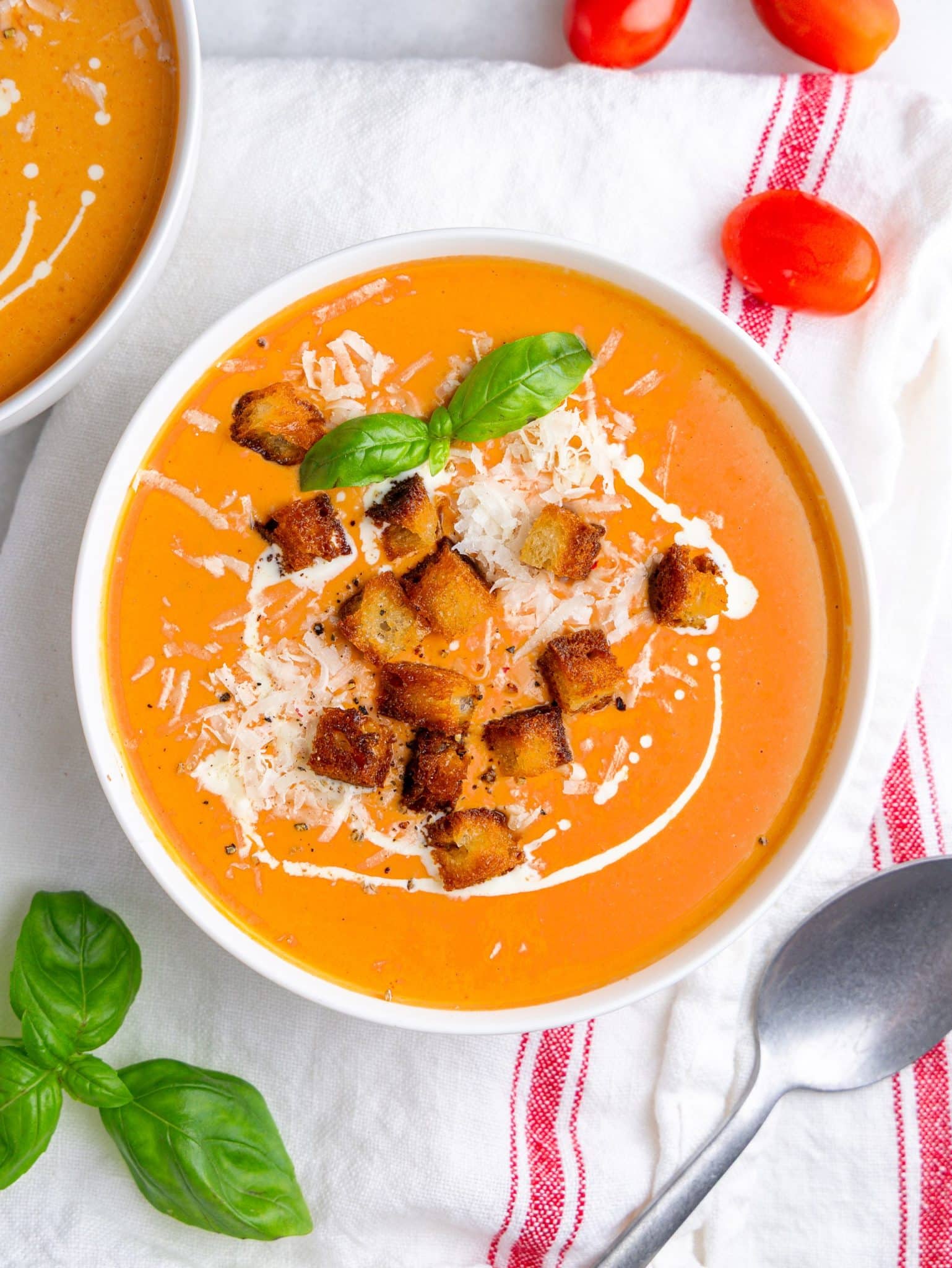 Bowl of high protein tomato soup with cottage cheese topped with croutons, parmesan, basil and a cream swirl