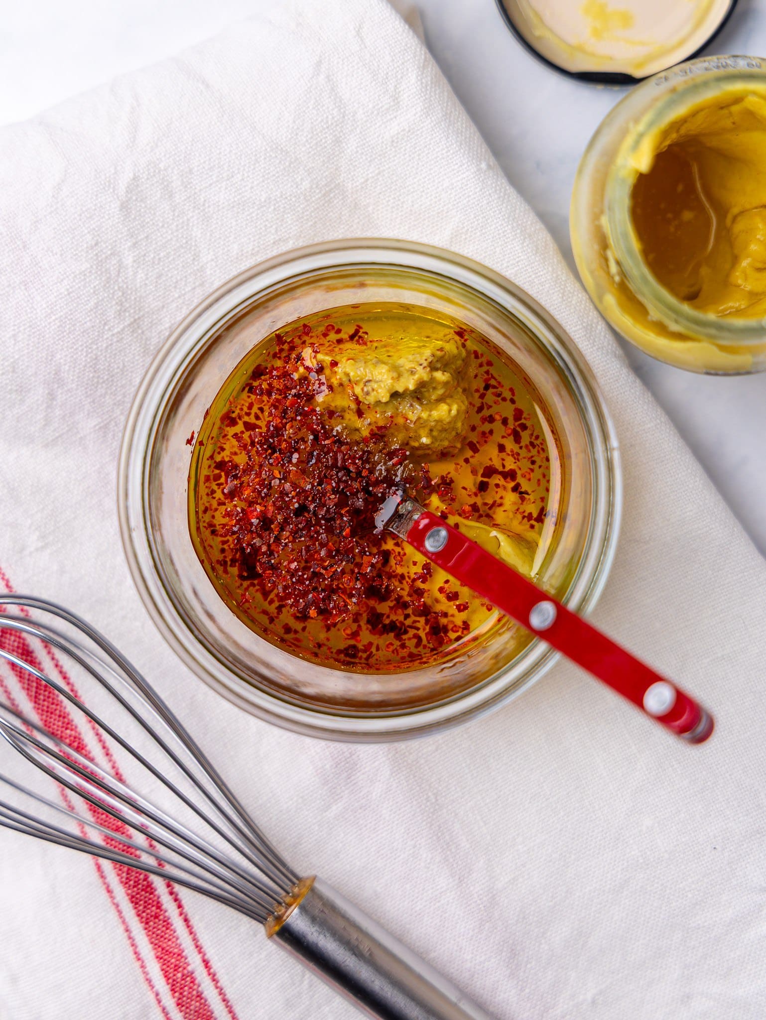 Garlic honey mustard dressing for autumn couscous salad in a small glass bowl with a whisk