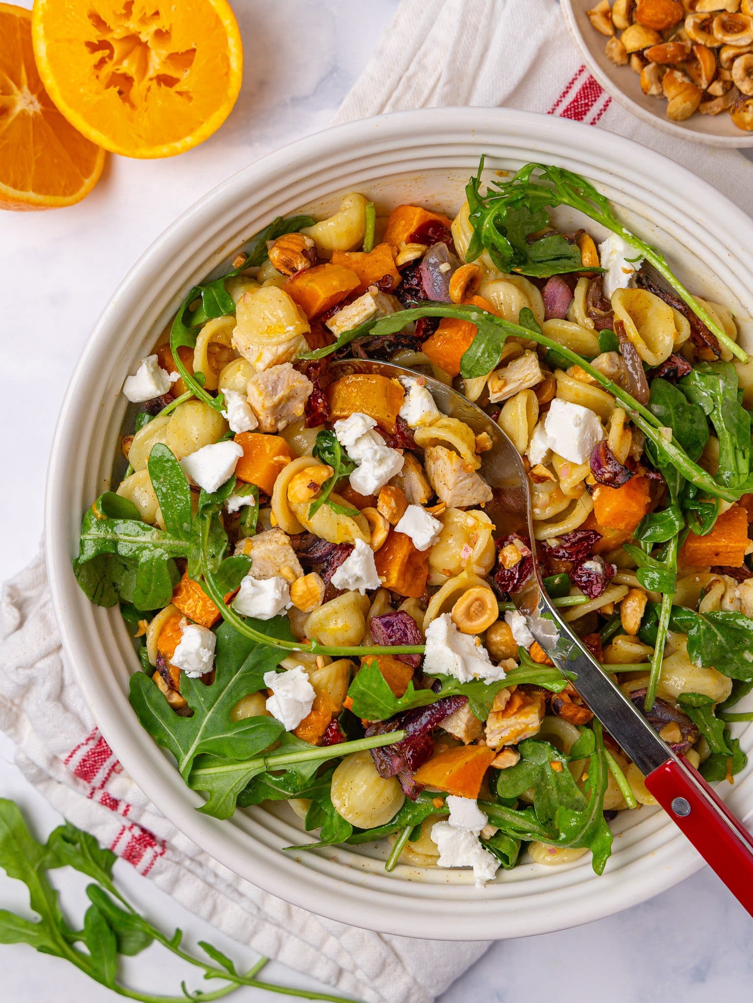 Autumn pasta salad with turkey, arugula and dried cranberries in a white serving bowl