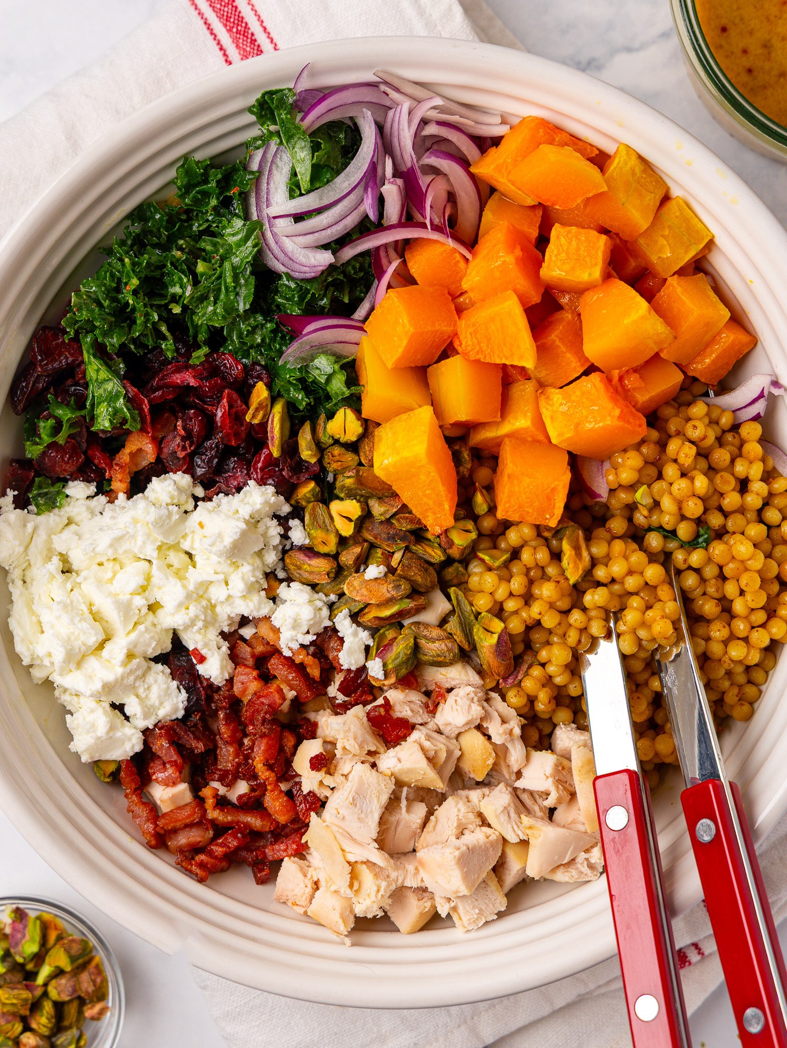 Autumn pearl couscous salad ingredients arranged in a bowl before tossing, with chicken, bacon, feta and squash