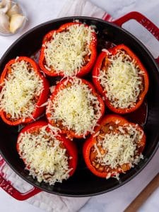 Easy stuffed peppers recipe before baking, six red peppers piled with shredded mozzarella