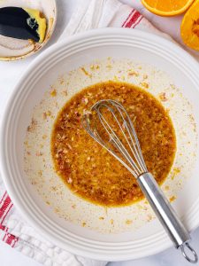 Fall pasta salad dressing with apple cider vinegar, orange and cinnamon whisked in a white bowl