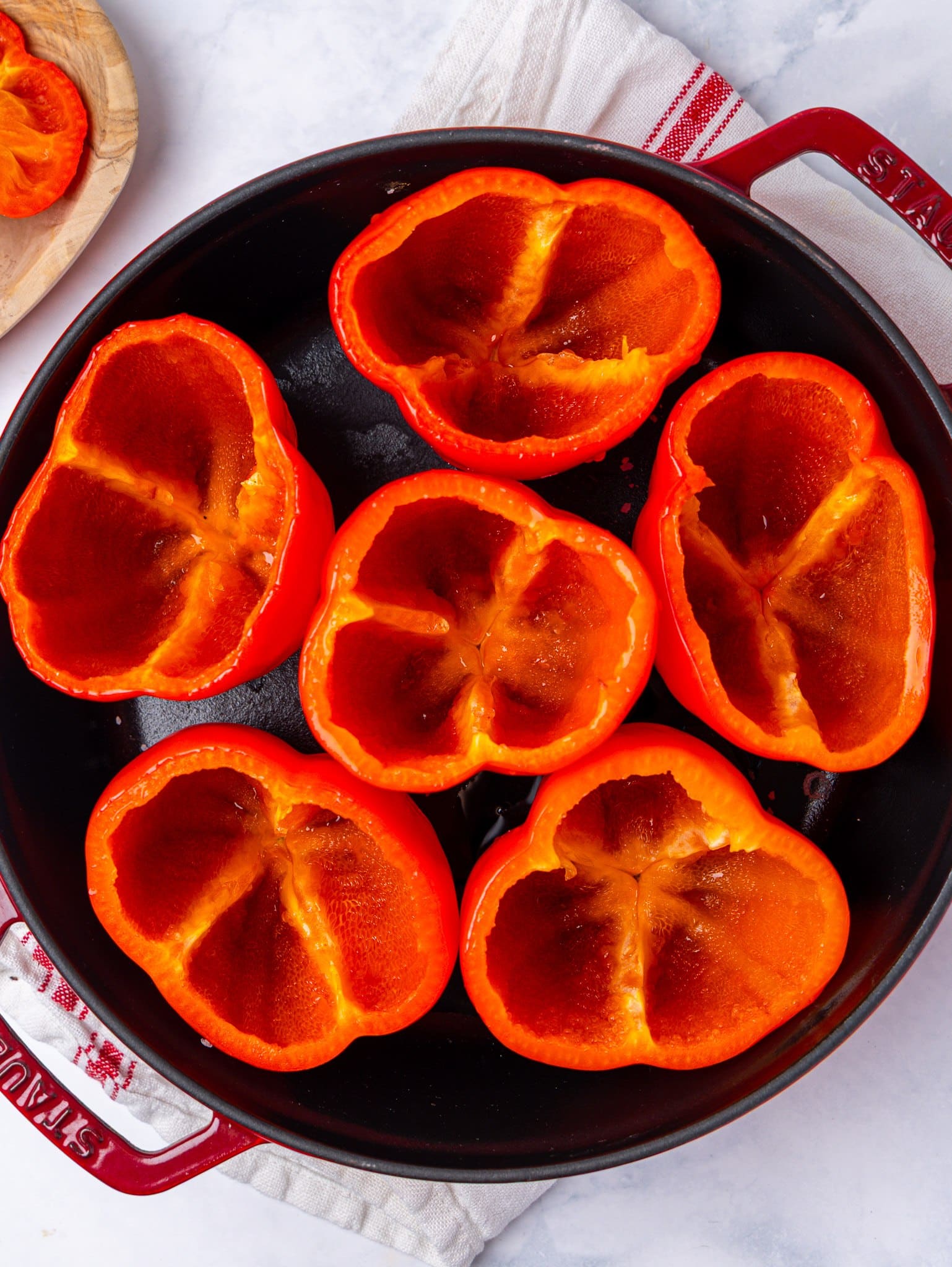 How to make stuffed peppers, starting with six hollowed red bell peppers standing in a cast iron pan