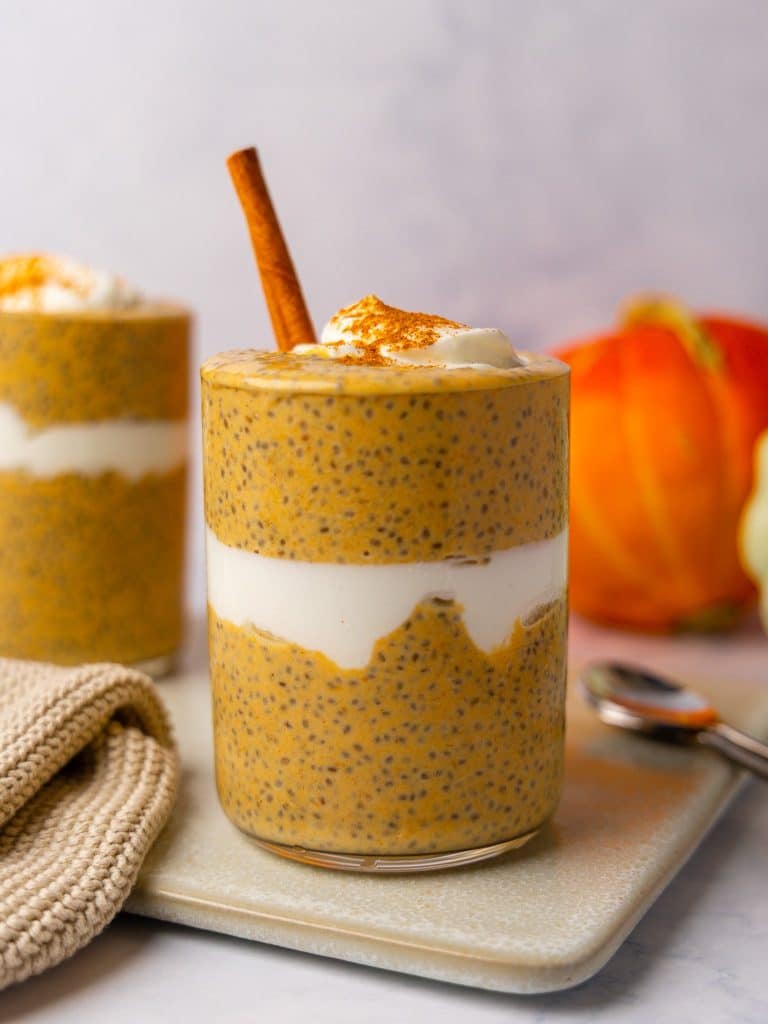 Pumpkin chia seed pudding layered with greek yogurt in a glass, topped with a cinnamon stick