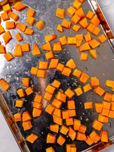 Roasted butternut squash cubes on a sheet pan for couscous salad