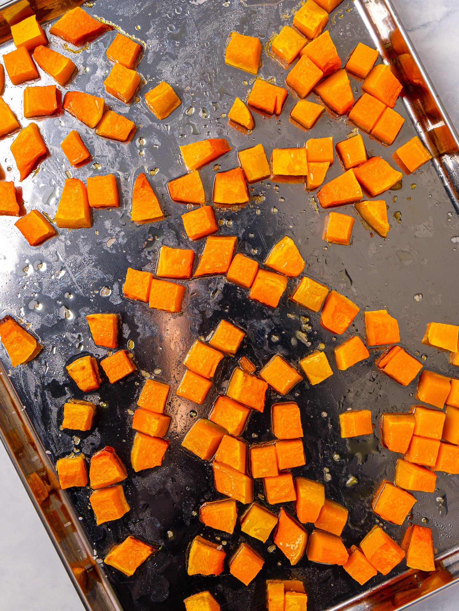 Roasted butternut squash cubes on a sheet pan for couscous salad