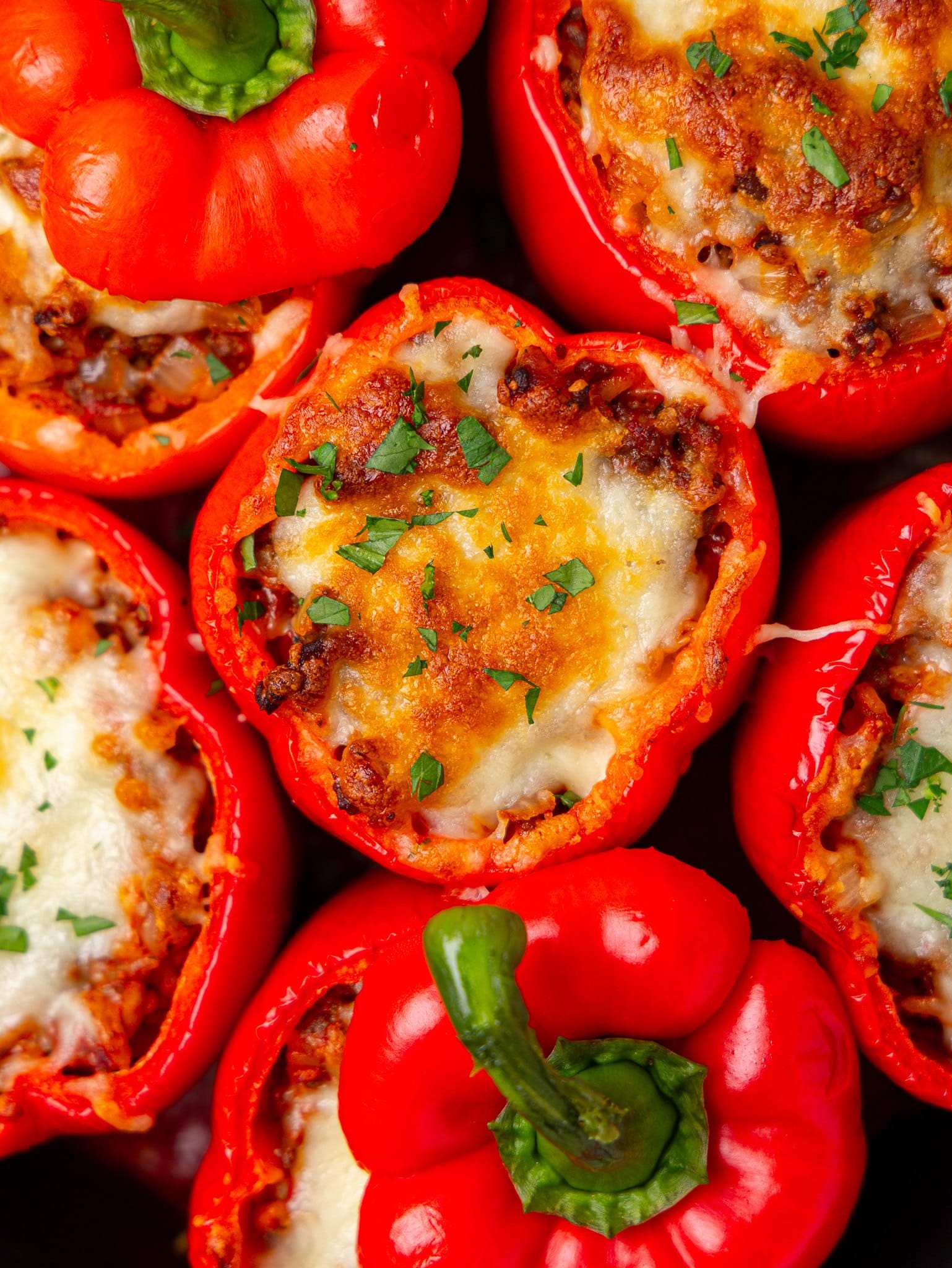 Close up of stuffed bell peppers with golden melted cheese and chopped parsley