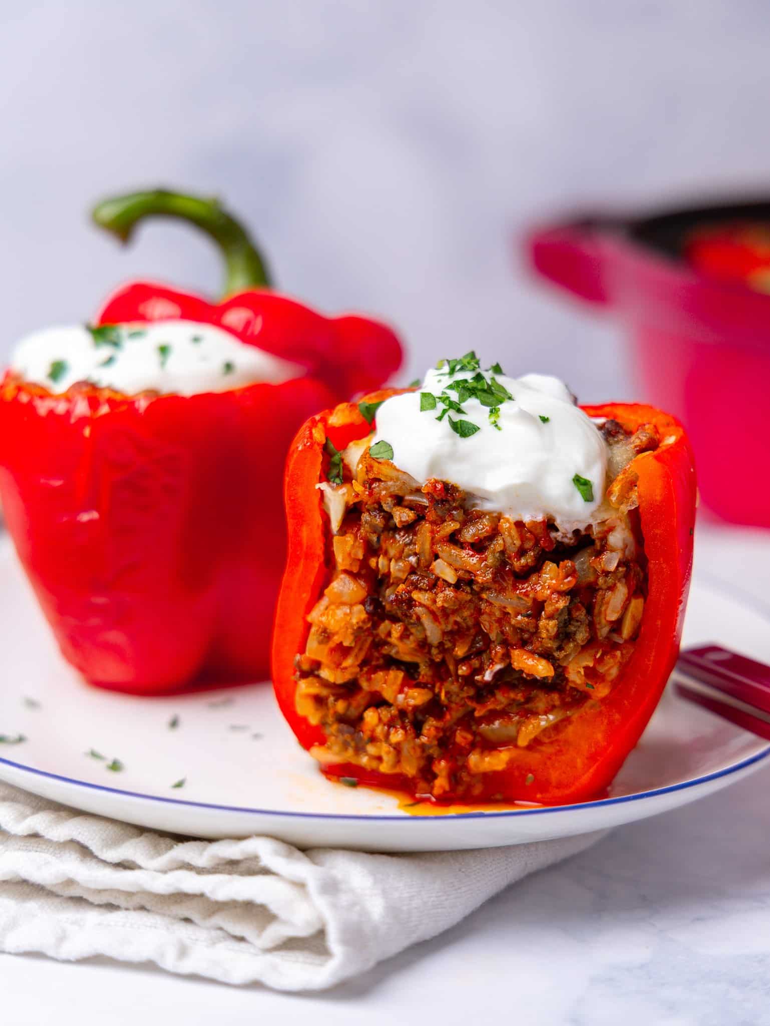Stuffed peppers with rice and ground beef, cut open on a plate with a dollop of greek yogurt