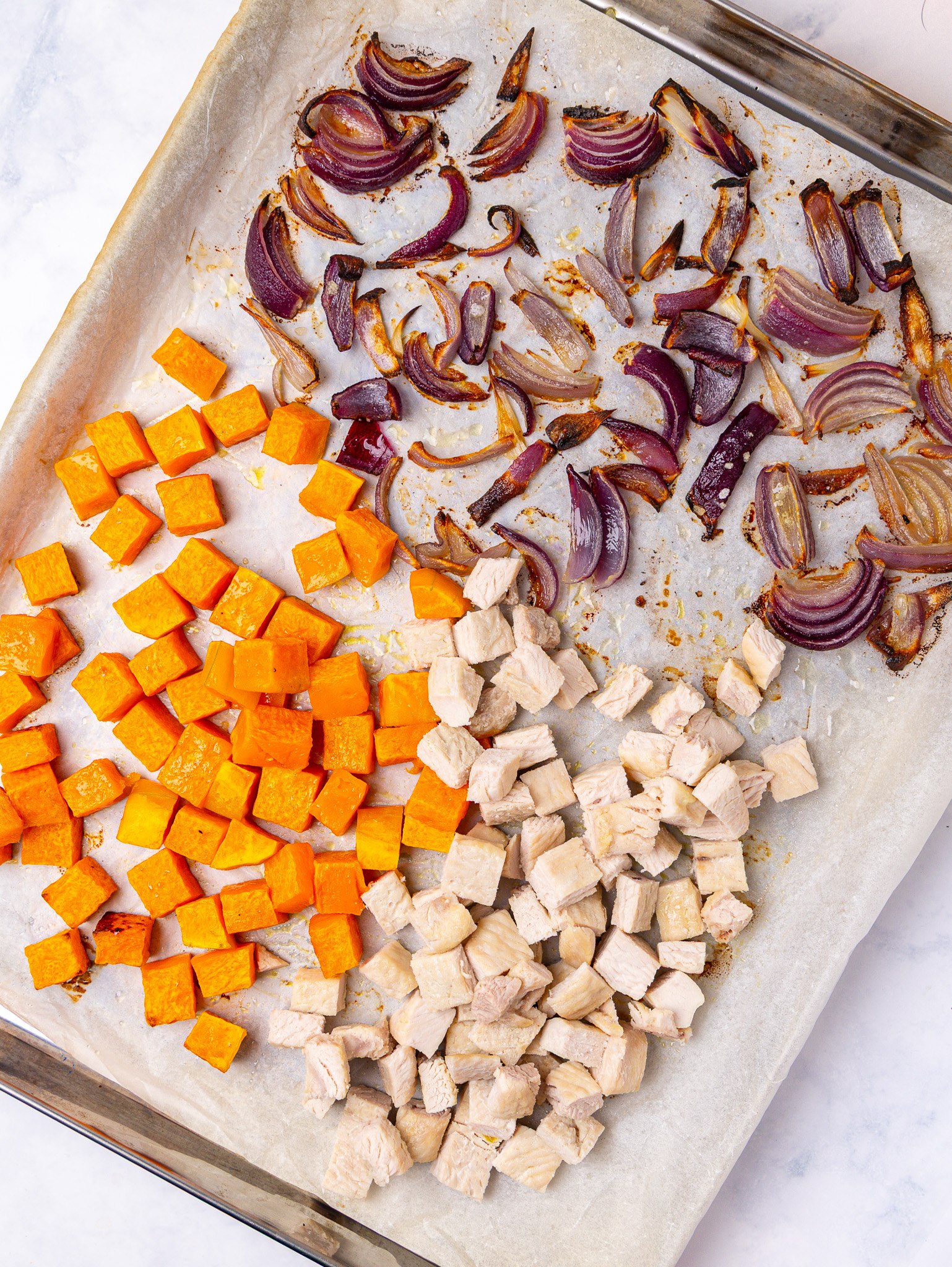 Roasted squash, red onion and diced turkey on a sheet pan, a base for Thanksgiving pasta salad recipes